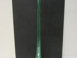 un vase en verre vert posé sur une surface noire