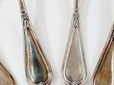 three silver spoons and a fork on a white surface