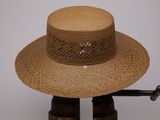 un chapeau de paille posé sur un support en bois, surmonté d'un autre chapeau