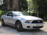 a silver mustang parked in front of a church