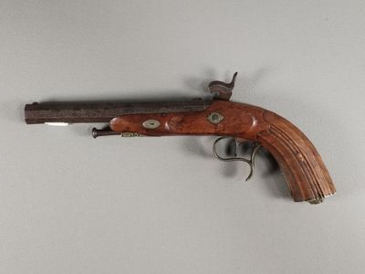 un petit pistolet en bois accroché au mur, à côté d'un mur blanc