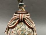 an image of a vase with a statue on top of it