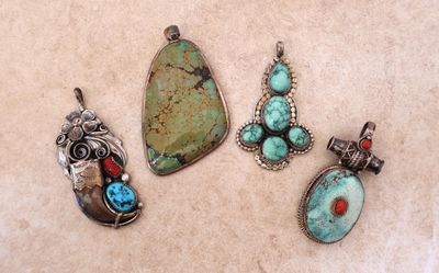 un ensemble de quatre pendentifs en pierres turquoise et rouges posés sur une table