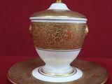 an image of a gold and white bowl and saucer on a red background