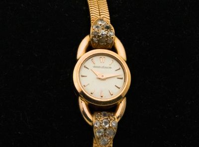 une montre-bracelet en or sertie de diamants, sur un fond noir