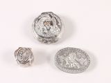 two silver buttons and a silver ring on a white surface