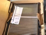 une boîte en carton contenant un radiateur, posée sur un tas de pneus