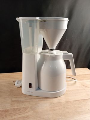 a white coffee maker sitting on a wooden table