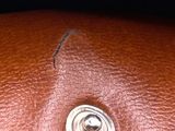a close up of a brown leather purse with a metal button