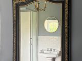 un miroir sur le mur au-dessus d'un lavabo dans une salle de bains