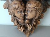 a wooden sculpture of two heads on a shelf