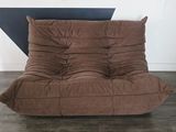 un fauteuil-futon marron dans une pièce aux murs noirs et blancs