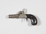 un petit pistolet posé sur une surface blanche