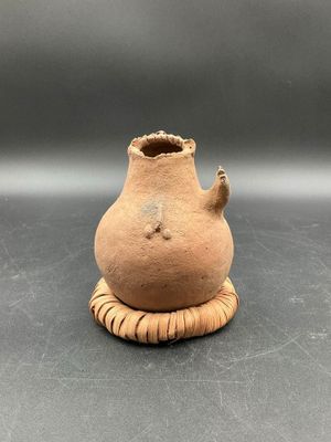 a small clay vase with a handle on a table