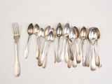 six silver spoons and a fork are lined up on a white surface