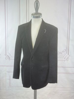 a suit on a mannequin stand in front of a white wall