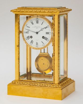 a gold clock with roman numerals and a glass case
