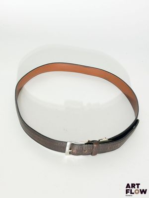 ceinture en cuir marron avec boucle argentée sur fond blanc