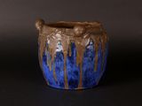 a blue and brown vase with a brown handle on a black surface