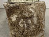 an image of a cement block with a face carved into it