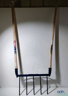 deux fourches suspendues à un râtelier fixé au mur