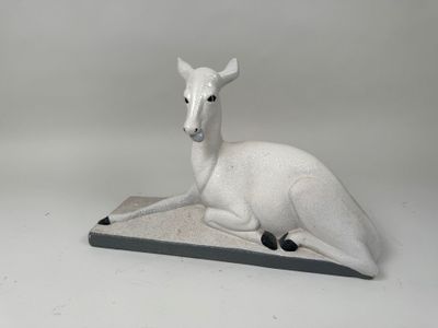 statue d'un cerf blanc assis sur une dalle de pierre