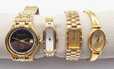 trois montres en or sont posées sur une serviette, sur une surface blanche