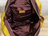 yellow and brown handbag sitting on a wooden table with a zipper open