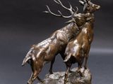 bronze sculpture of two stagss on a rock on a grey background