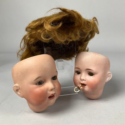 deux têtes de poupées avec des cheveux, posées sur un socle