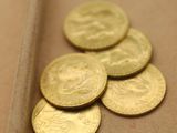 un tas de pièces d'or posées sur une table, à côté d'un couteau