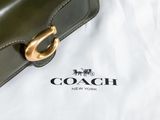 a coach bag sitting on top of a white sheet