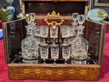bottles and glasses in a wooden case on a red table cloth