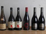 several bottles of wine are lined up on a wooden table