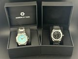 two watches in a box with a chain on a table
