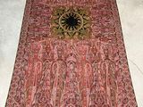 rug on the floor in a room with a chair and a table in the background