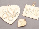 two gold heart shaped pendants with initials and a small heart