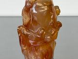 une petite statue représentant un homme assis sur un rocher
