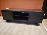 a black tv stand with a black door and a brown wall in the background