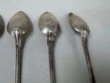 four spoons are lined up in a row on a white surface