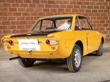 a yellow car that is parked in front of a brick wall