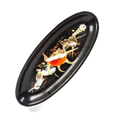 une assiette ovale noire ornée d'un poisson doré et de fleurs
