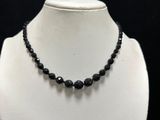 a close up of a necklace with black beads on a mannequin
