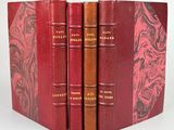 trois livres rouges sont empilés sur une surface blanche