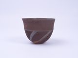 un bol marron posé sur une surface blanche