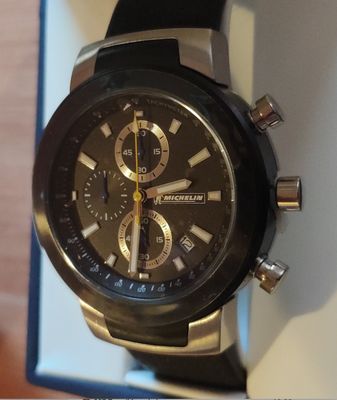 La montre est noire et possède un cadran doré.