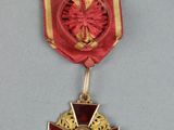 une image représentant une médaille rouge et dorée ornée d'une croix