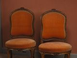 pair of orange upholstered chairs in front of a red wall