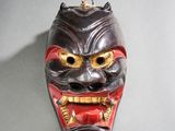 un masque accroché au mur, représentant un visage rouge et noir
