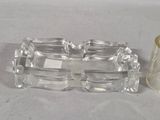 a glass ashtray and a glass candle holder on a table